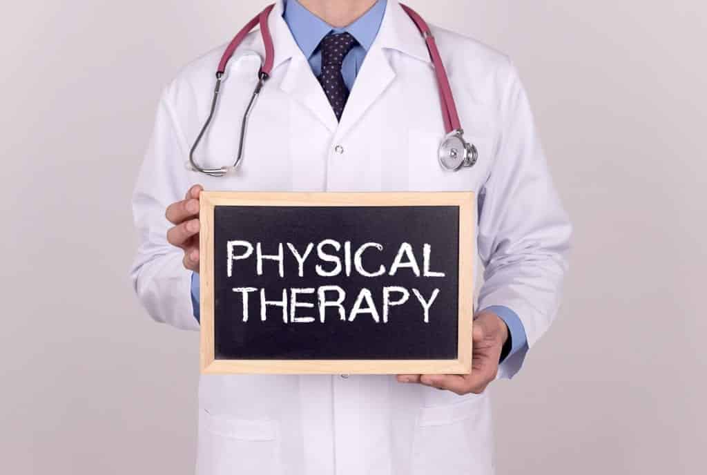 Doctor holding mini blackboard with PHYSICAL THERAPY message